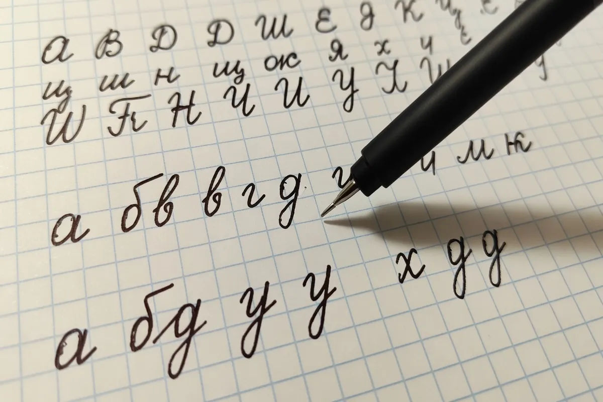 Gros plan sur lettres cursives cyrilliques tracées à la main sur papier quadrillé